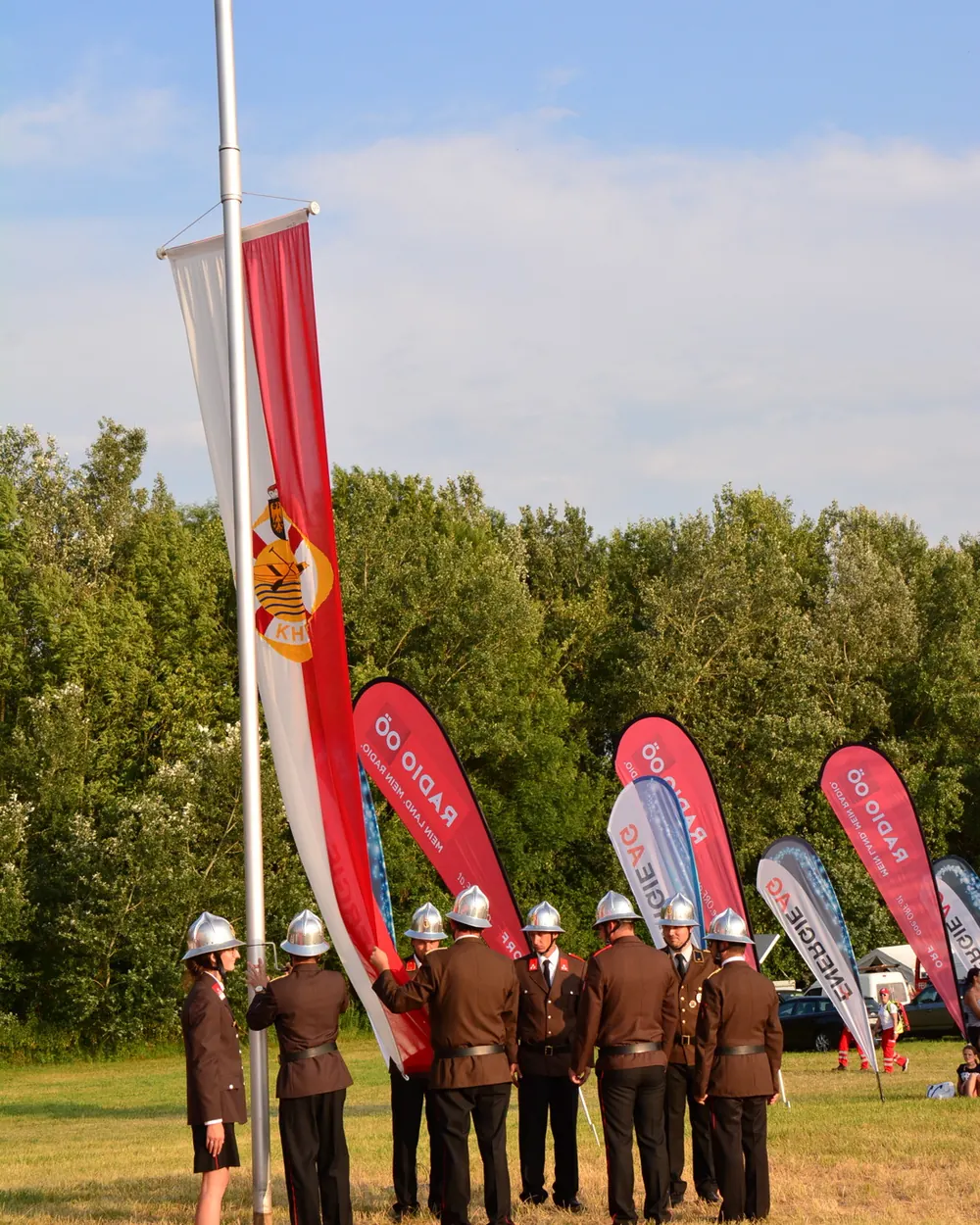 Feuerwehrleute in Uniform holen eine Fahne am Mast ein