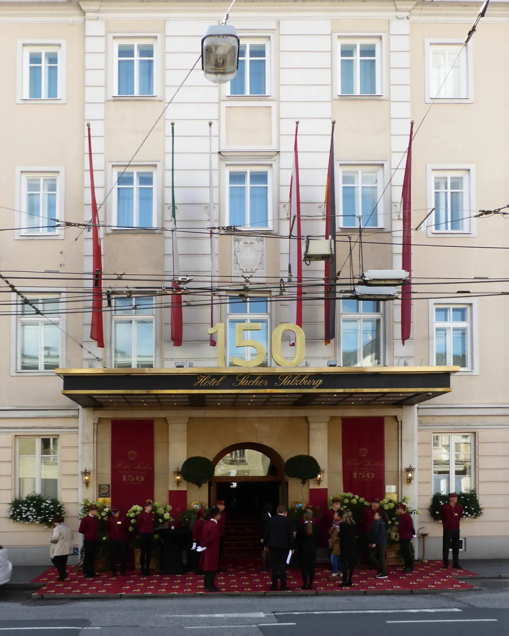 Fassade des Hotel Sacher in Salzburg mit vielen roten Fahnen an Auslegern