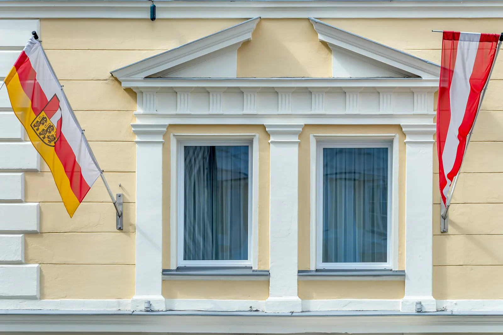 Kärntner Landesfahne und Österreichfahne an Auslegern an einer Hausfassade in Klagenfurt