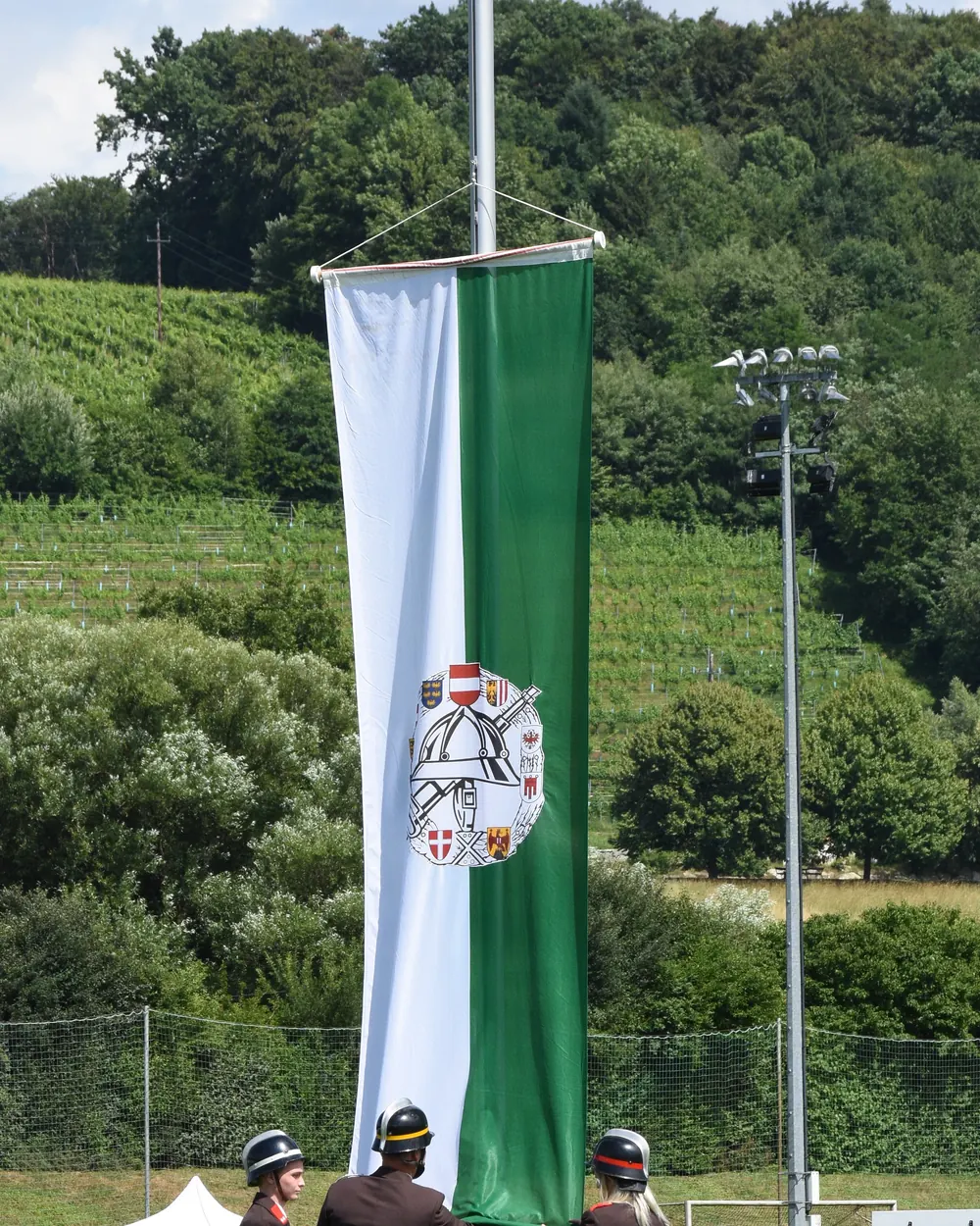Feuerwehrleute hissen die grün-weiße steirische Landesfahne an einem Mast