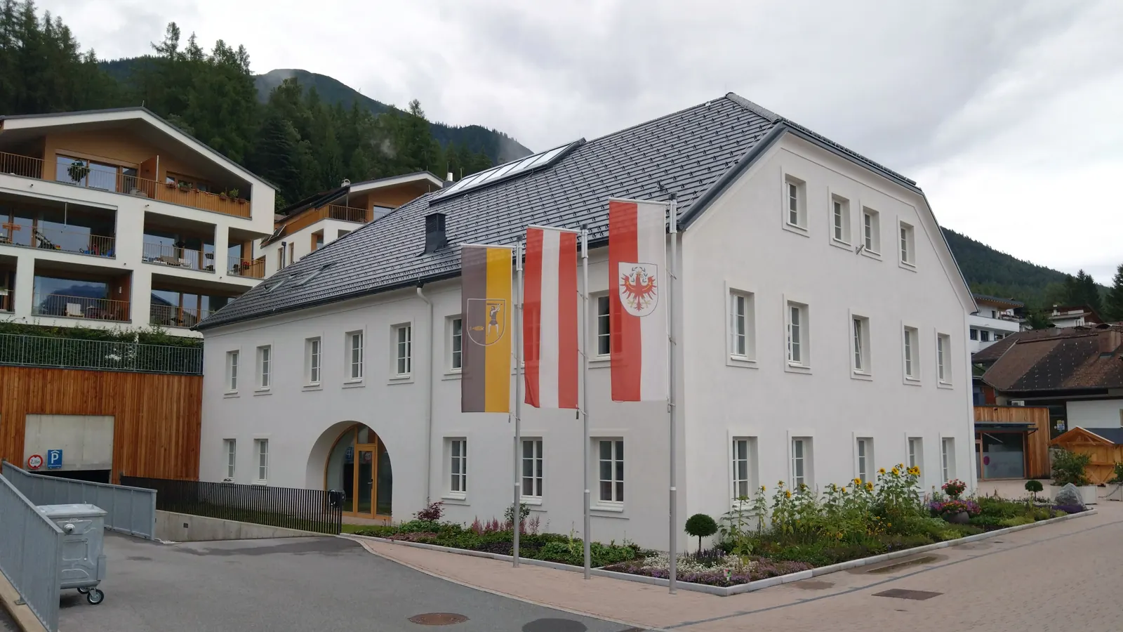 Gemeindeamt Reith bei Seefeld mit Gemeindefahne, Österreichfahne und Tiroler Landesfahne an drei Masten, die Österreichfahne in der Mitte