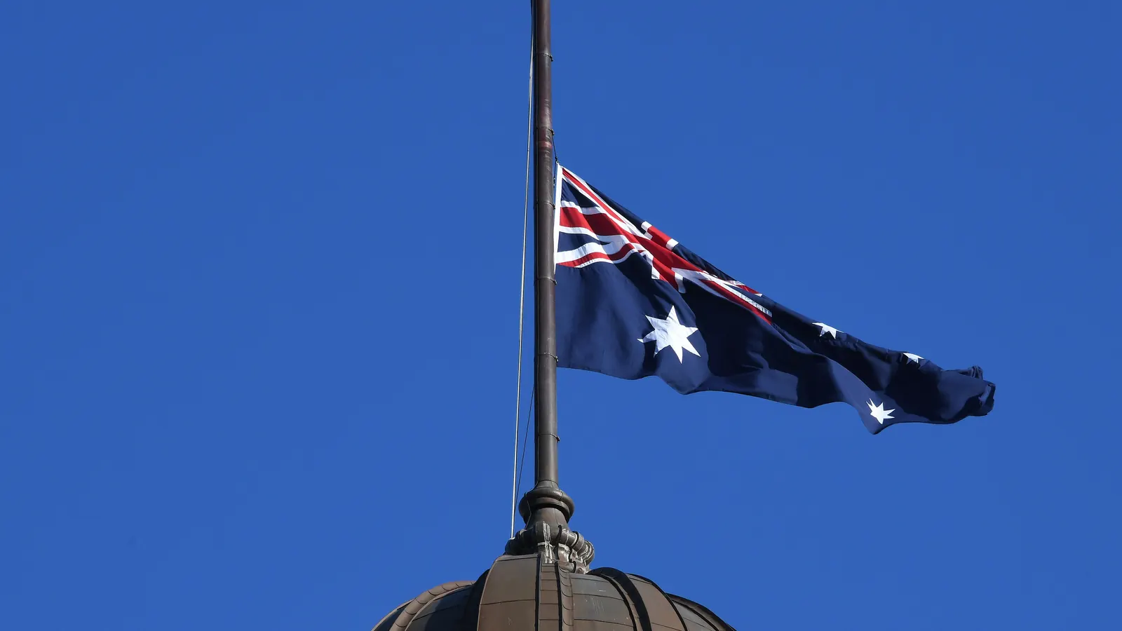 The Australian National Flag at half-mast against the sky at Central Station, Sydney