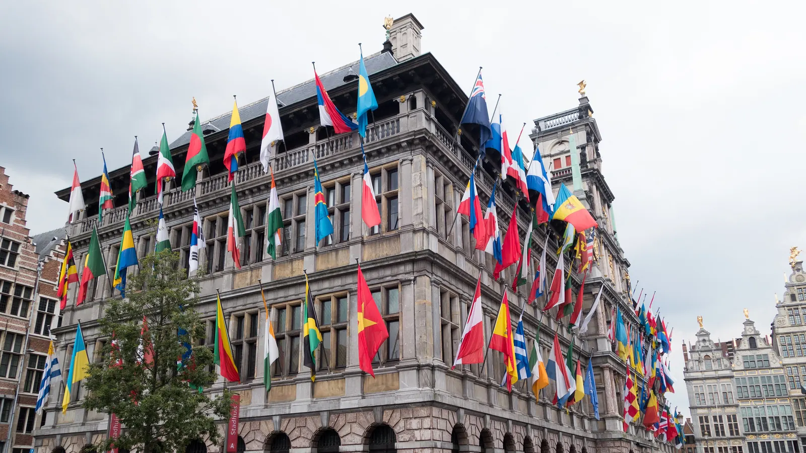 Het stadhuis van Antwerpen met vlaggen van tientallen landen aan de gevel