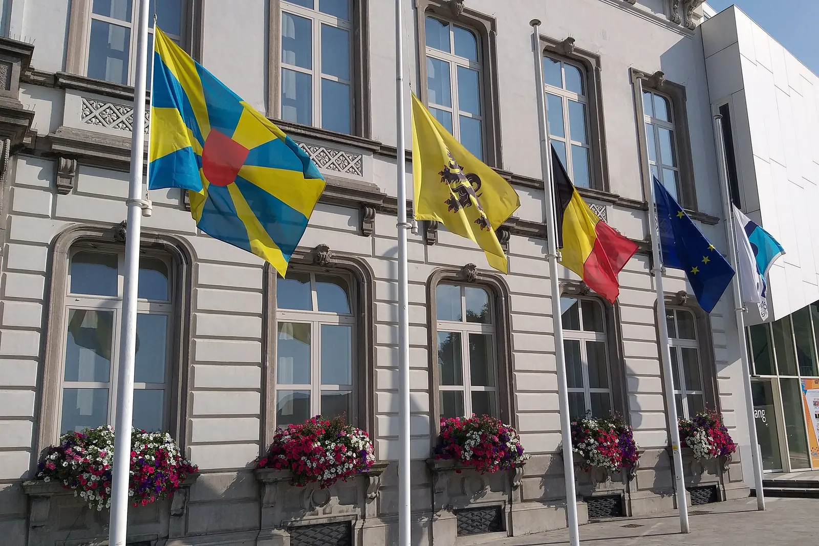 Vlaggen halfstok aan masten voor het stadhuis van Harelbeke
