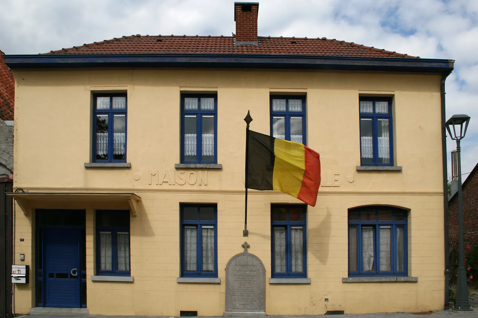 Het voormalige gemeentehuis van Vellereille-le-Sec met de Belgische vlag aan de gevel