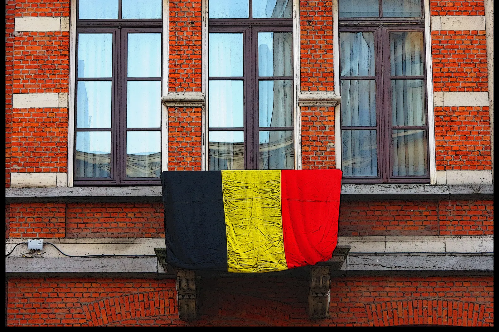 De Belgische vlag hangt over een balkon aan een bakstenen gevel in Antwerpen