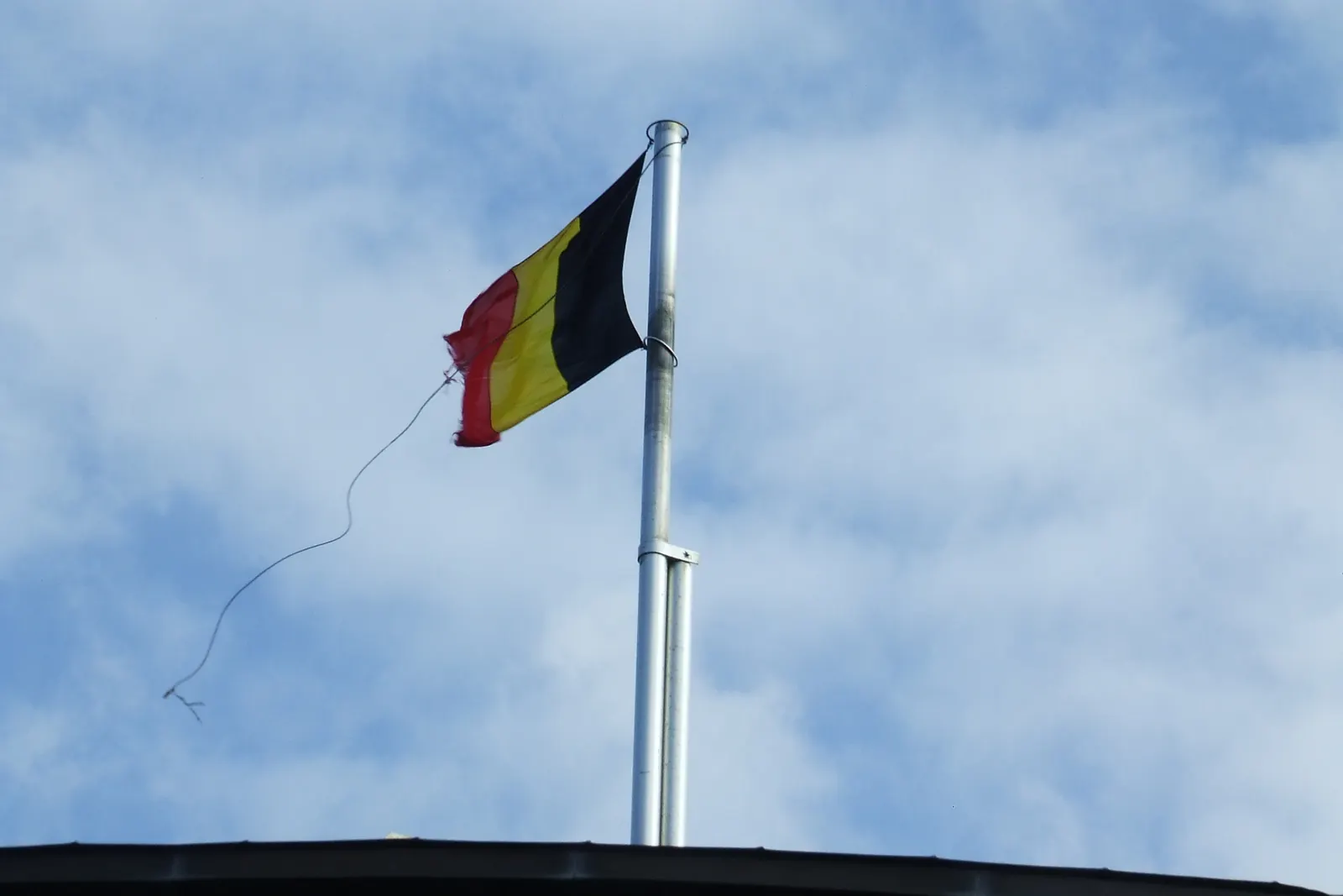De Belgische vlag aan een mast op de pier van Blankenberge tegen een lichte lucht