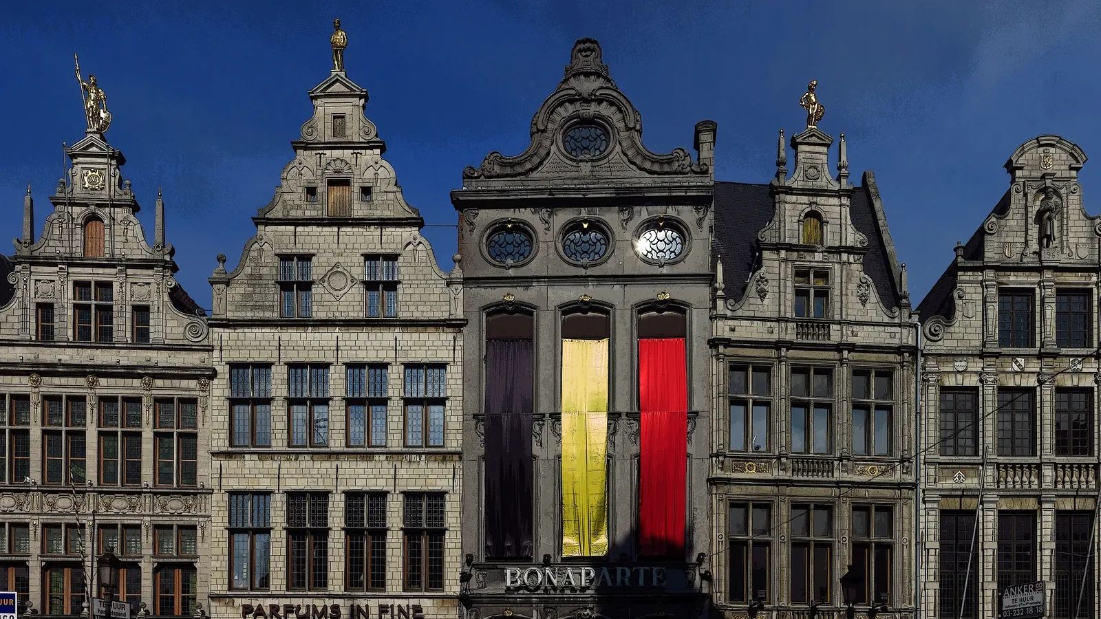 Een grote Belgische vlag hangt aan de gevel van een gildehuis op de Grote Markt in Antwerpen