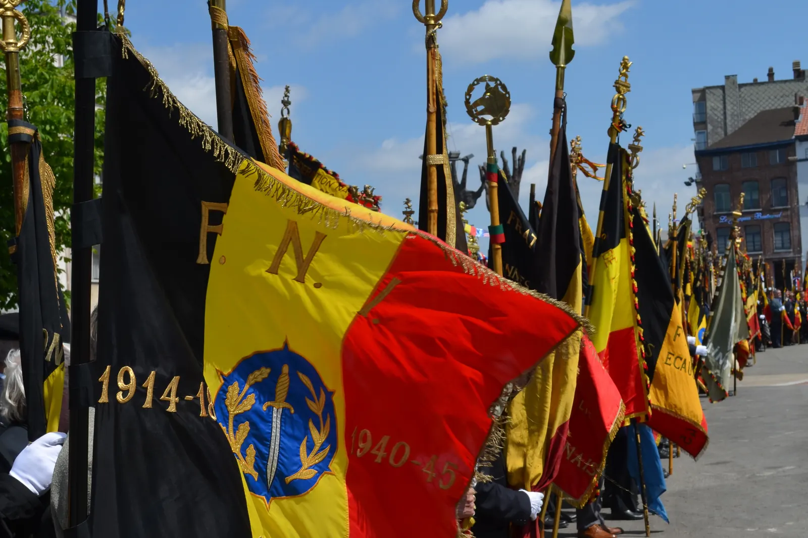 Een rij vaandeldragers met Belgische vaandels tijdens een plechtigheid in Charleroi