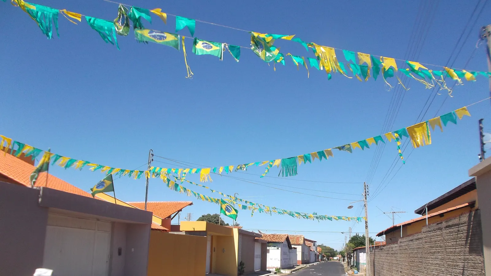 Uma rua residencial enfeitada com bandeirinhas e fitas verde e amarelas
