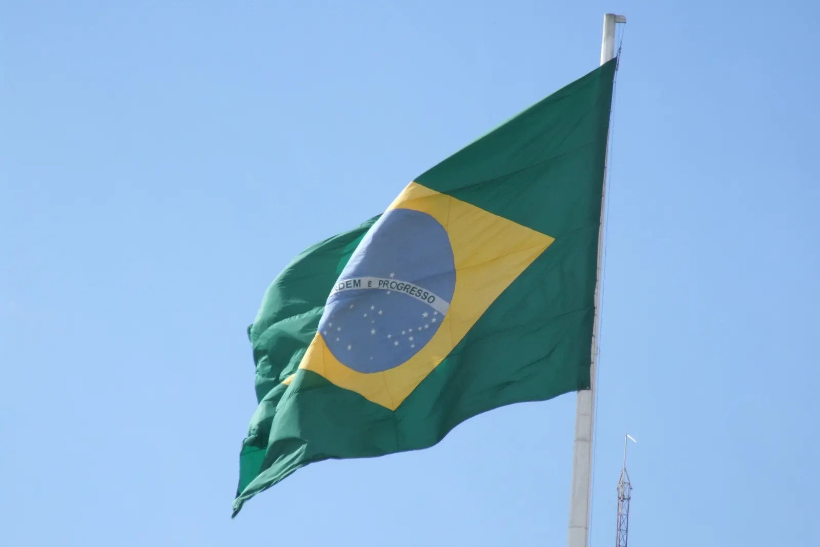 A bandeira verde, amarela, azul e branca em um mastro contra o céu azul
