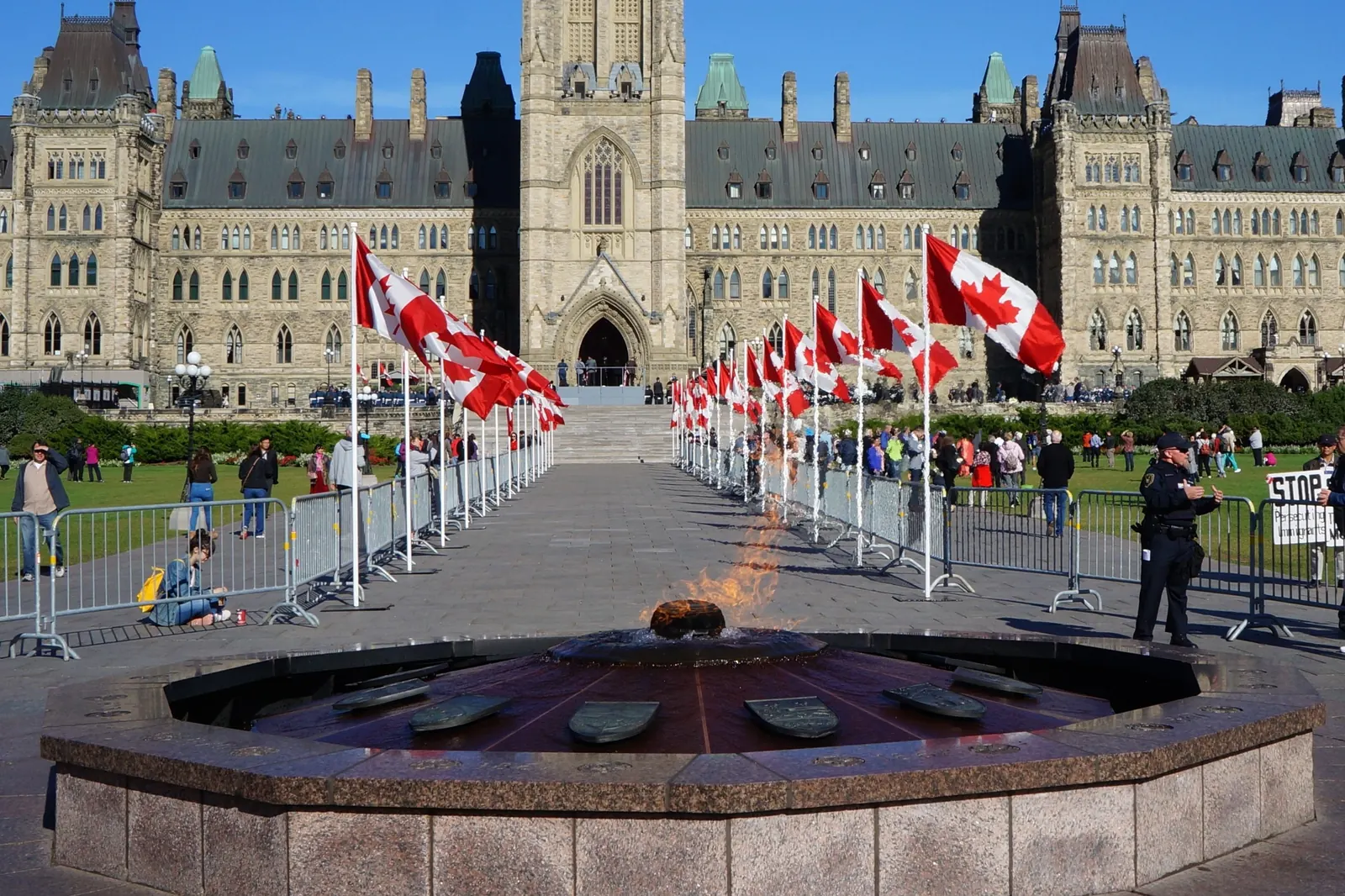 The Centennial Flame in front of the Parliament Buildings in Ottawa, with rows of Canadian flags along the walk