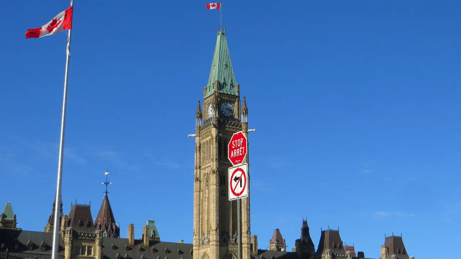 The Peace Tower on Parliament Hill in Ottawa with the flag of Canada on top and a flagpole beside the Centre Block