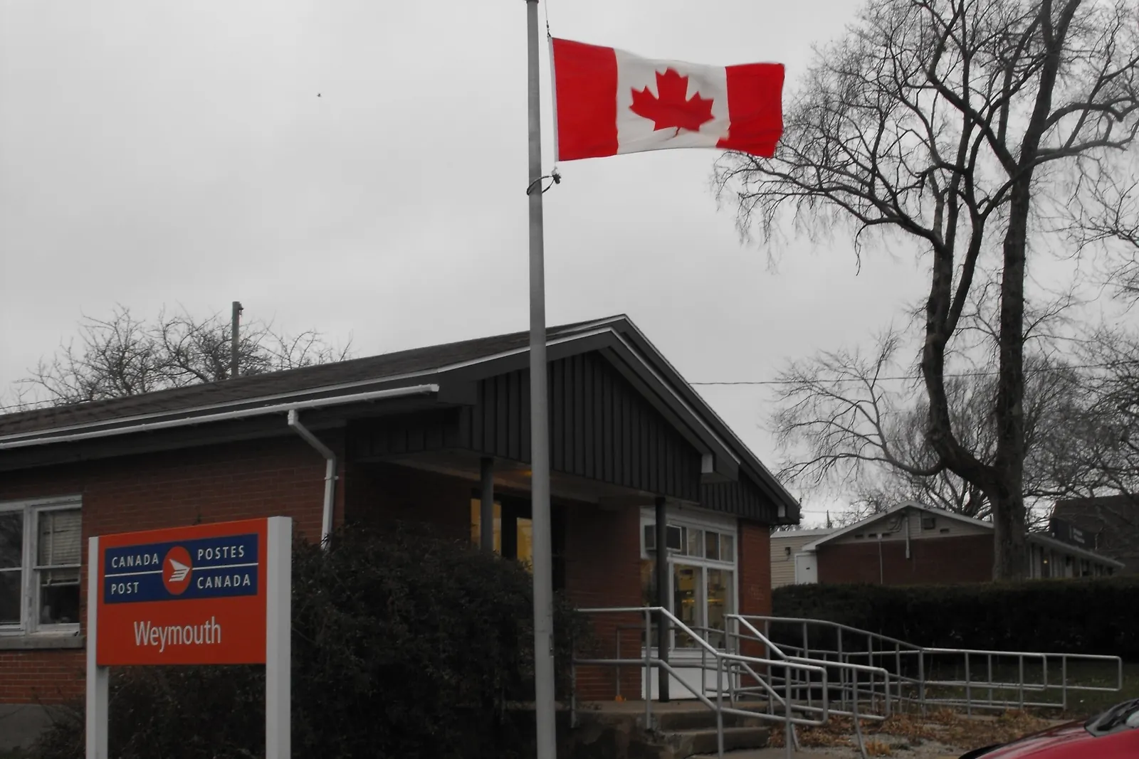 The post office in Weymouth, Nova Scotia, with the flag of Canada on a flagpole by the entrance
