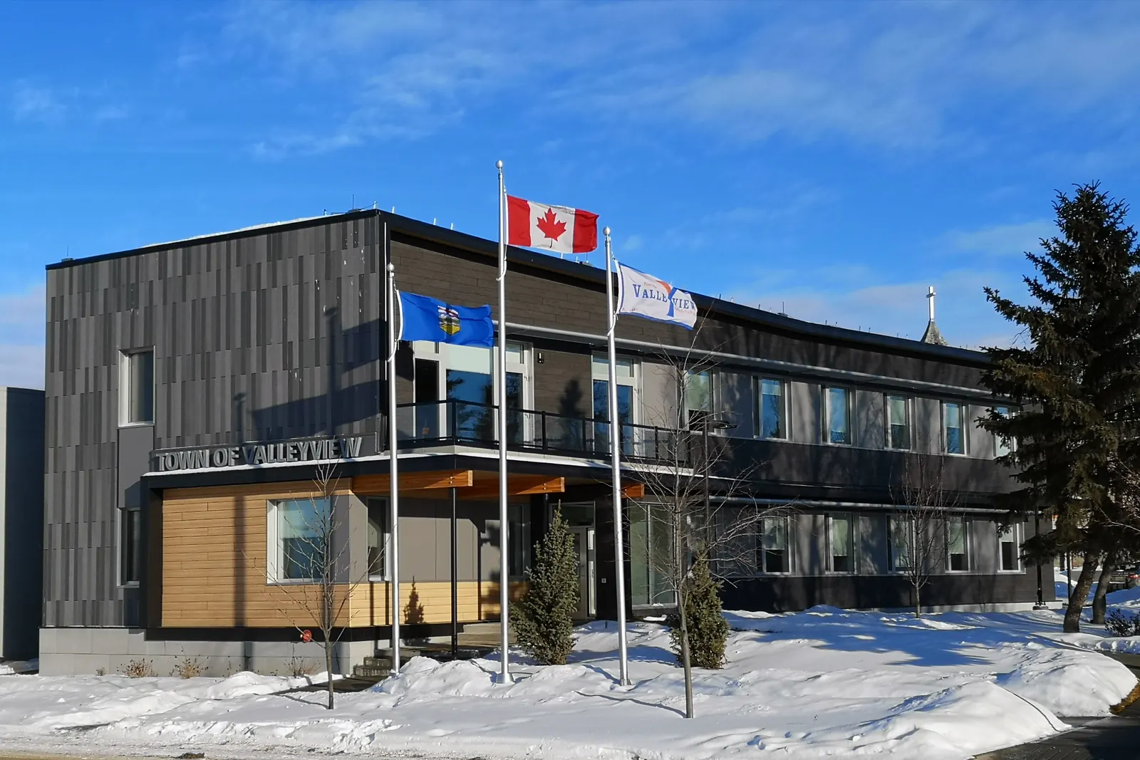 The town hall in Valleyview, Alberta, with the flags of Canada, Alberta and the town on three flagpoles in the snow