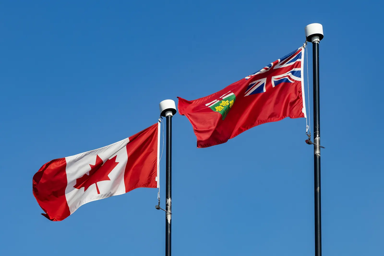The flags of Canada and Ontario side by side on two flagpoles in Windsor, Ontario