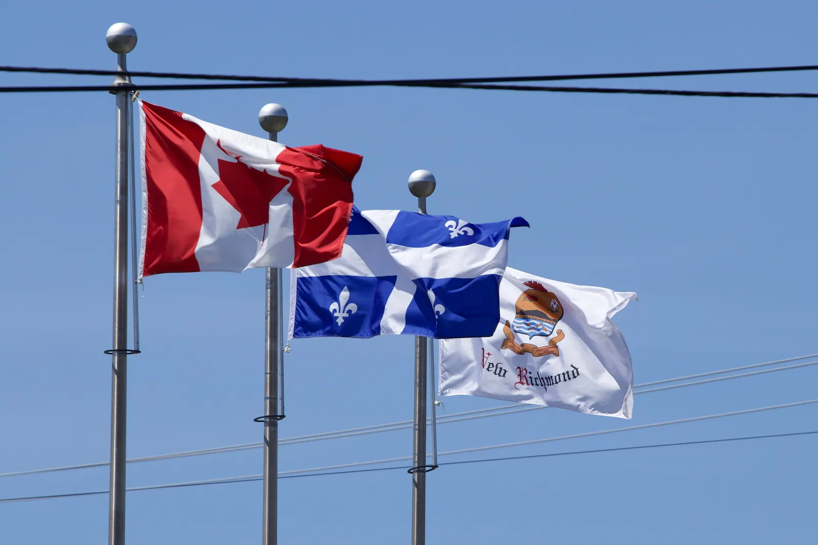 The flags of Canada, Québec and the town of New Richmond on three flagpoles