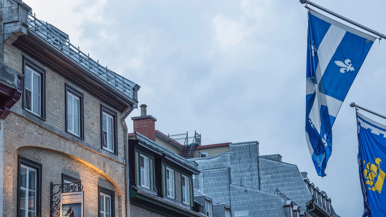 The fleurdelisé, the flag of Québec, on a pole from a facade in Old Québec