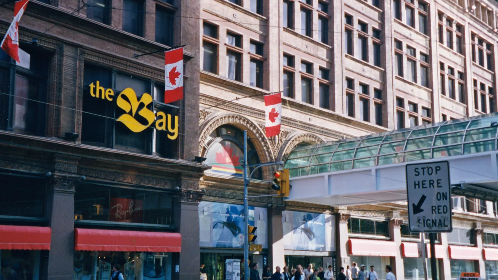 The Bay department store on Queen Street in Toronto with Canadian flags on poles from the facade