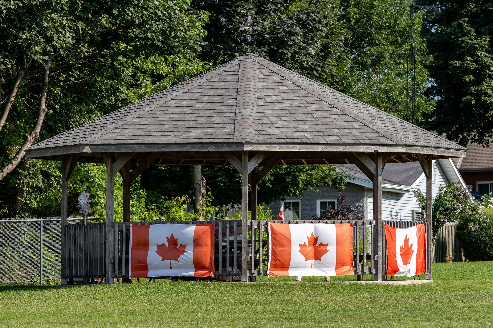 A gazebo in a park in Leamington, Ontario, hung with three Canadian flags