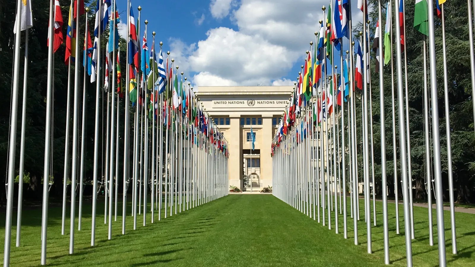 Die Fahnen der Mitgliedstaaten an zwei Reihen von Masten vor dem Palais des Nations in Genf