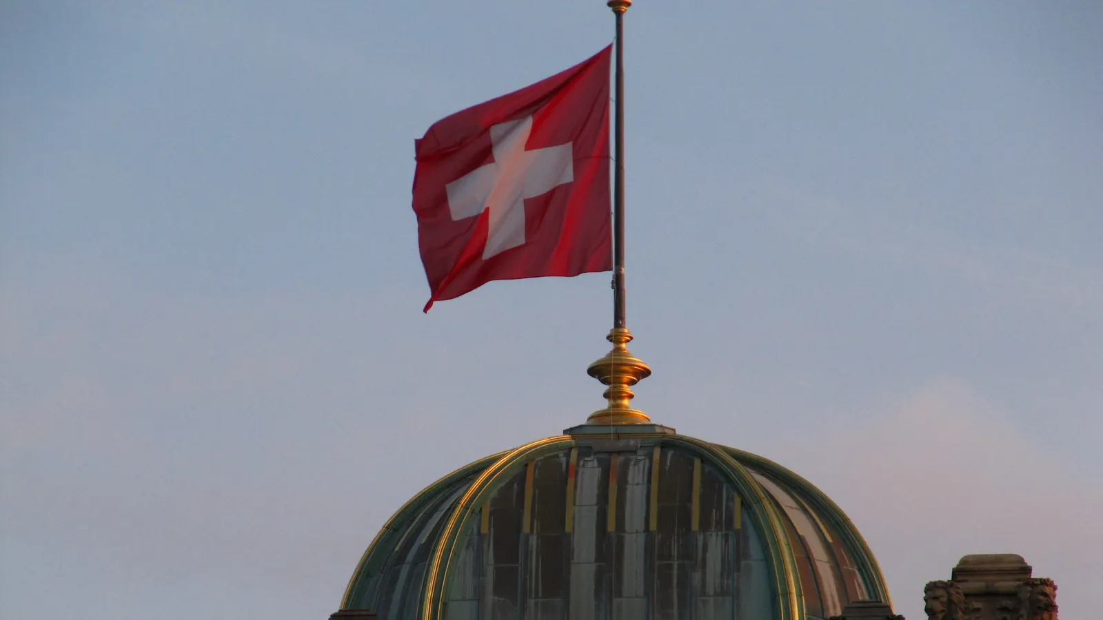 Die Schweizerfahne auf der Kuppel des Bundeshauses in Bern im Abendlicht