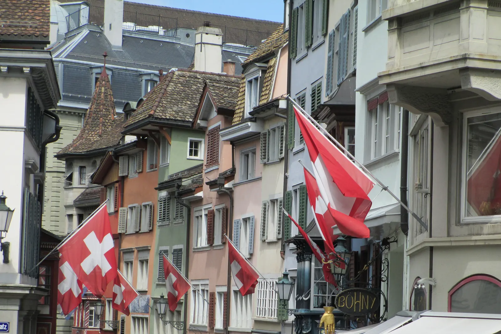 Schweizerfahnen an Auslegern an den Häusern einer Altstadtgasse in Zürich
