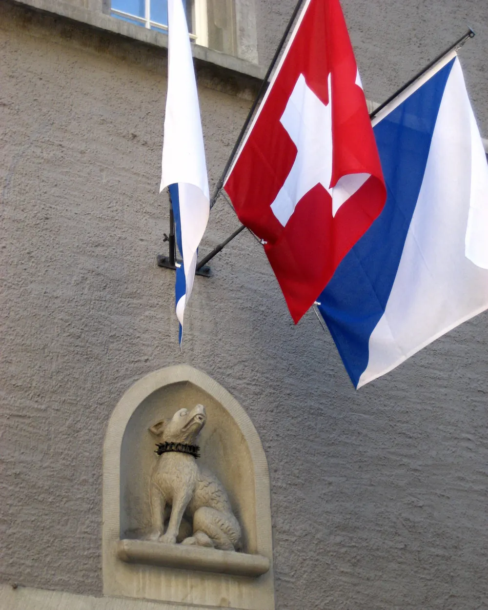 Schweizerfahne und Zürcher Fahne an Auslegern an der Steinfassade des Hauses zum Rüden