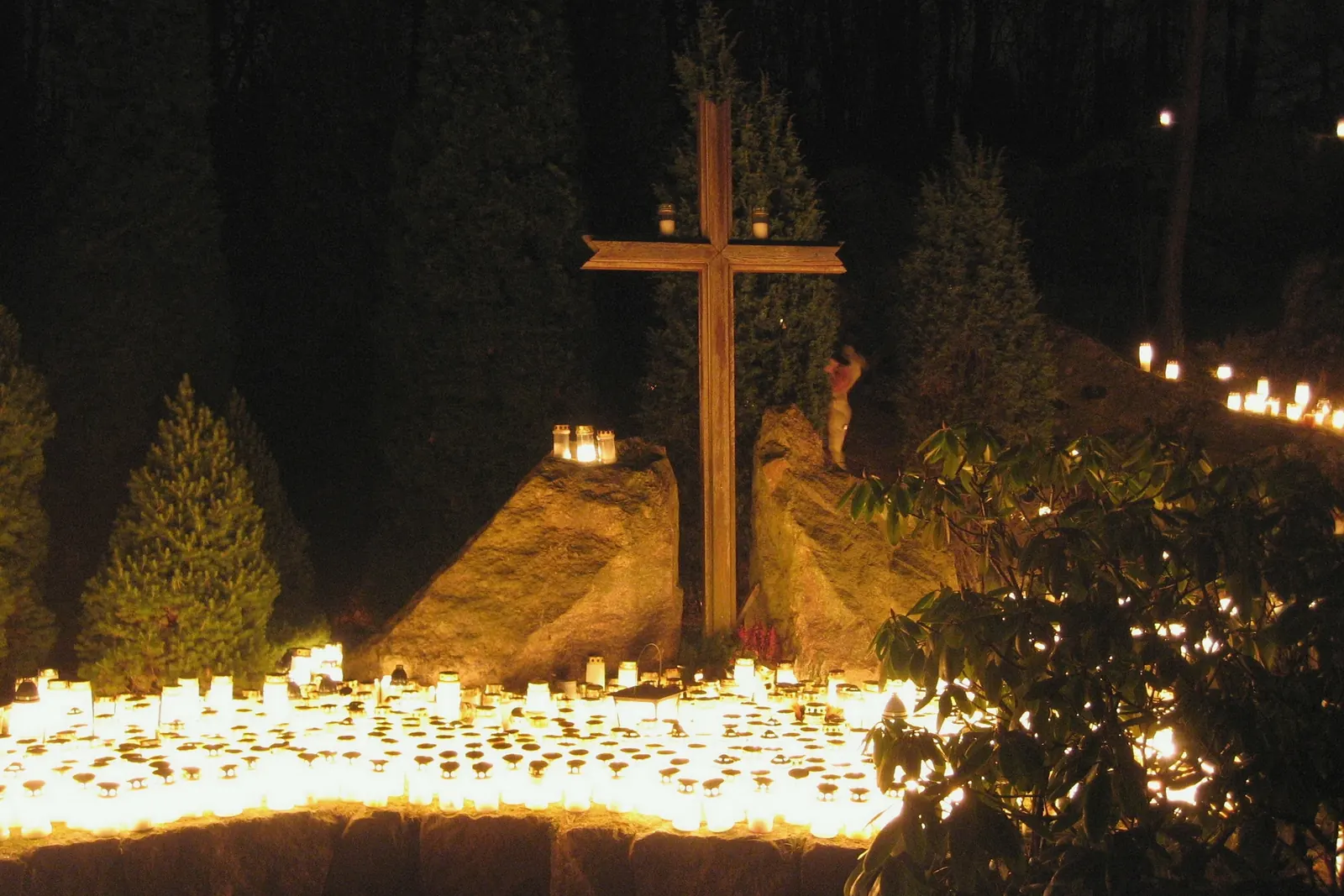 Velas encendidas ante una cruz en un cementerio
