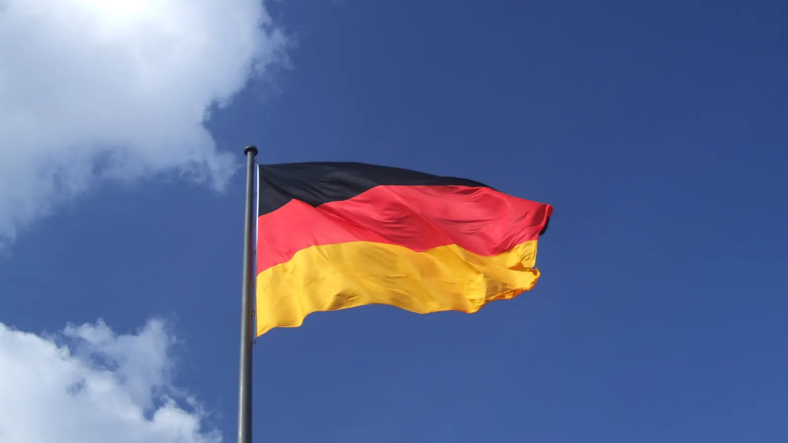 Die Bundesflagge weht an einem hohen Mast vor dem Reichstagsgebäude in Berlin