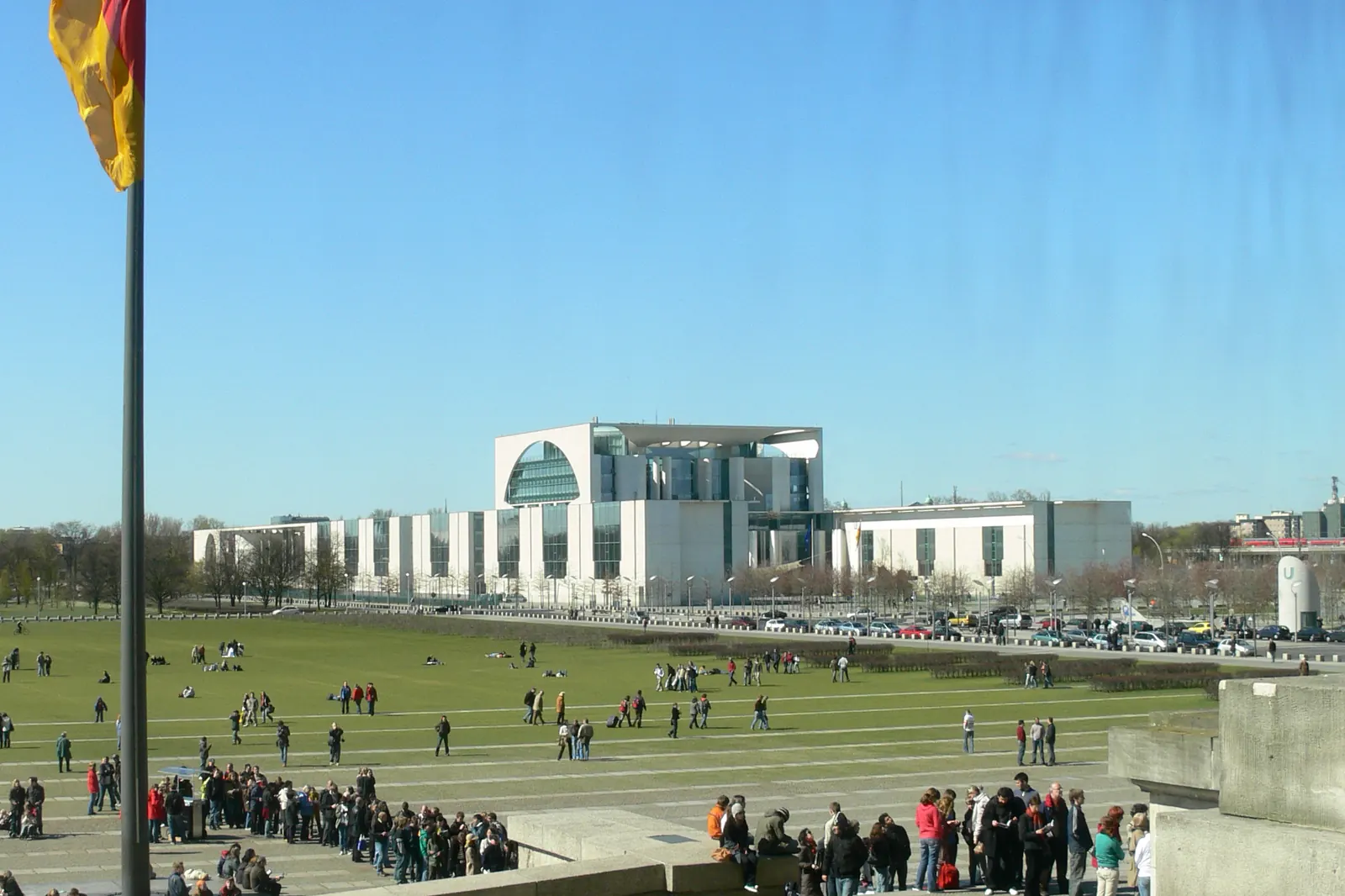Blick vom Reichstagsgebäude über die Wiese zum Bundeskanzleramt, links die Bundesflagge an einem hohen Mast
