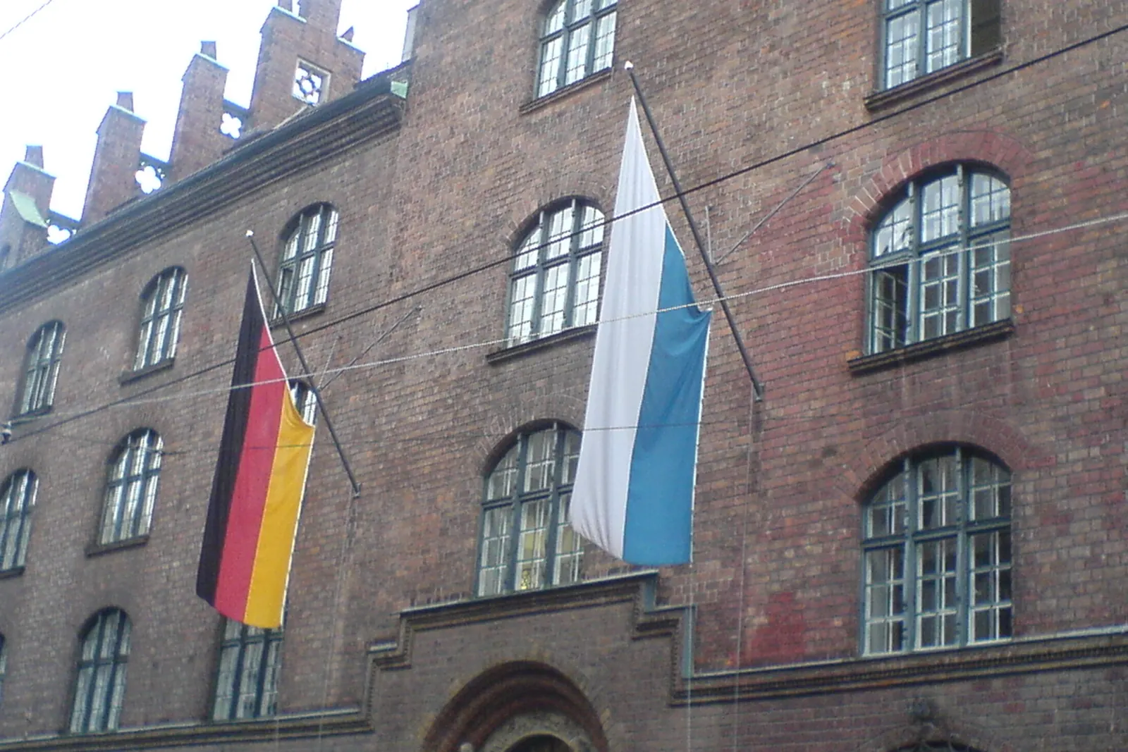 Bundesflagge und bayerische Flagge an Auslegern an der Fassade des Neuen Justizgebäudes in München