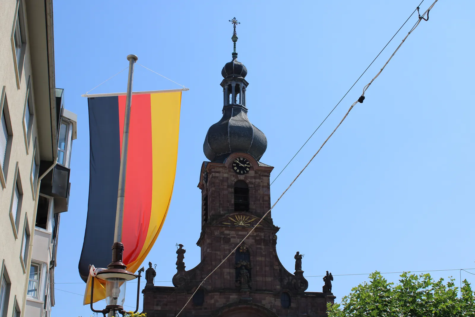 Schwarz-rot-goldene Fahne an einem Mast vor dem Turm einer Kirche in Rastatt