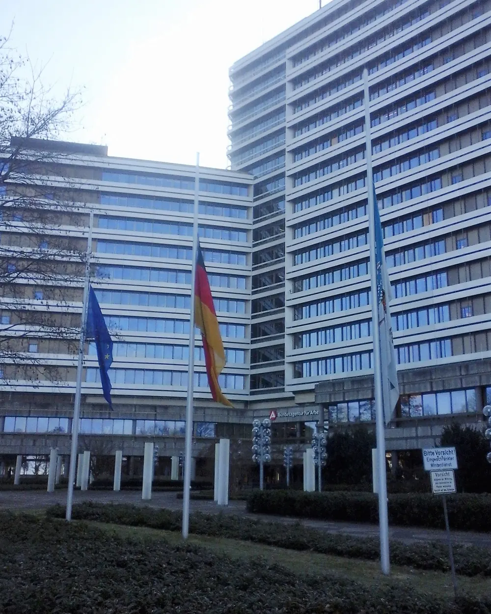Europaflagge und Bundesflagge auf halbmast vor dem Hochhaus der Bundesagentur für Arbeit, rechts eine weitere Flagge