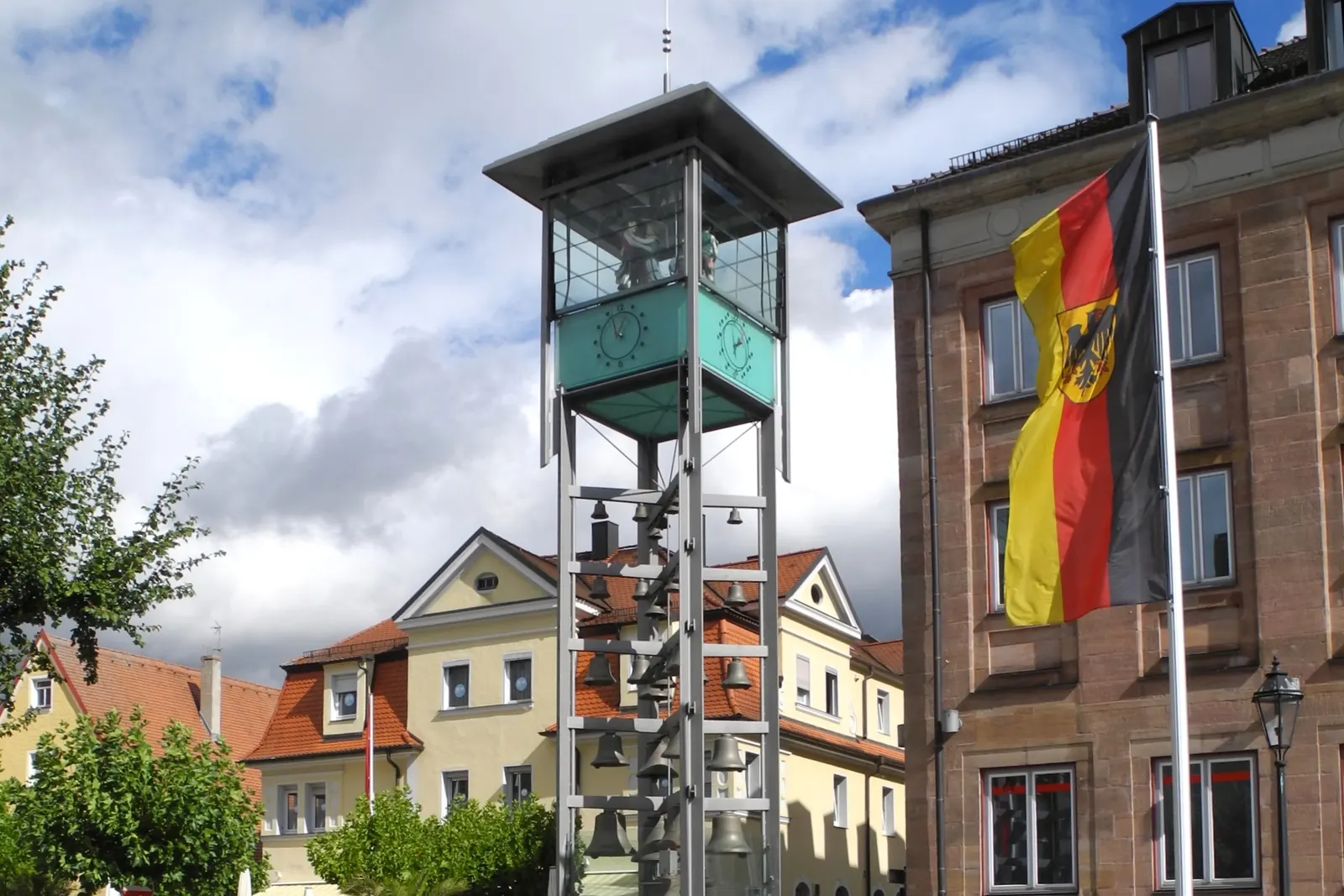 Bundesdienstflagge mit Bundesschild an einem Mast neben dem Glockenspiel am Marktplatz in Gunzenhausen