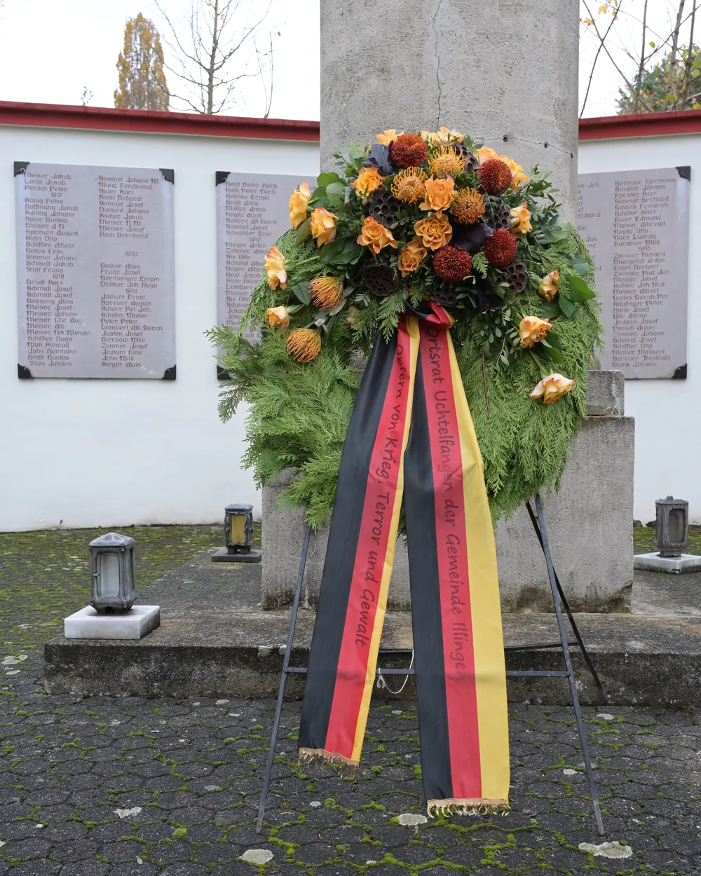 Kranz mit schwarz-rot-goldener Schleife vor einem Ehrenmal
