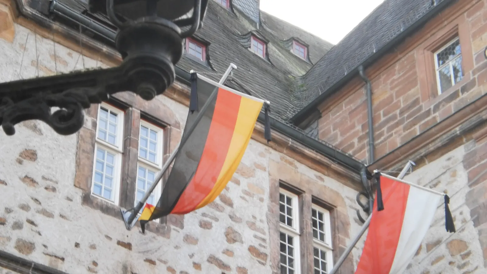 Bundesflagge und hessische Landesflagge mit schwarzem Trauerflor an Auslegern am Rathaus Marburg