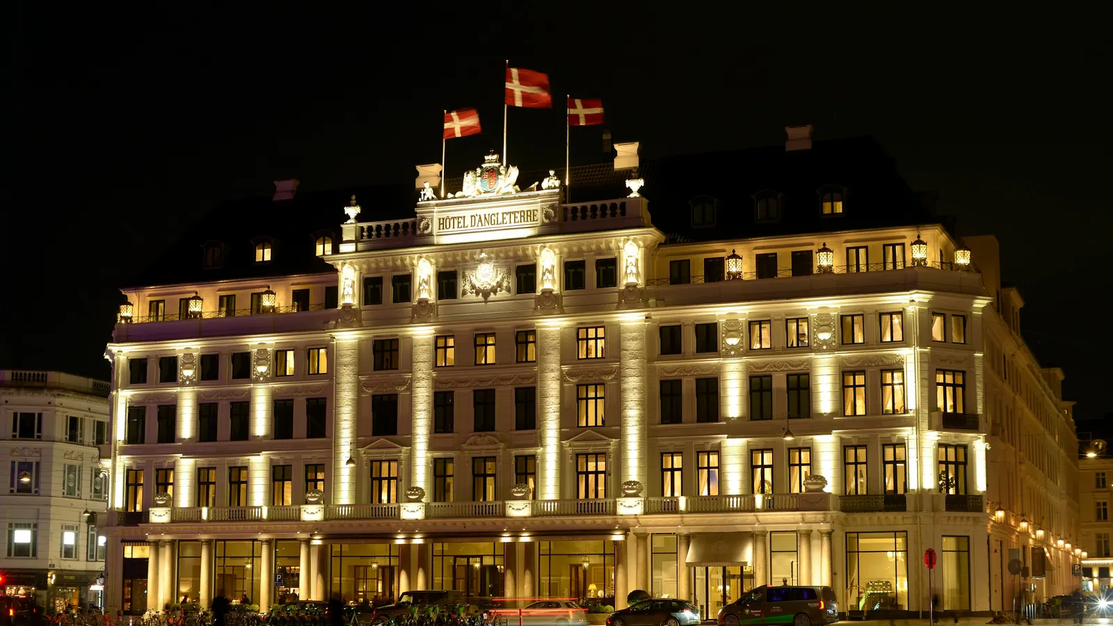 Oplyst hotelfacade i København om aftenen med dannebrogsflag på taget
