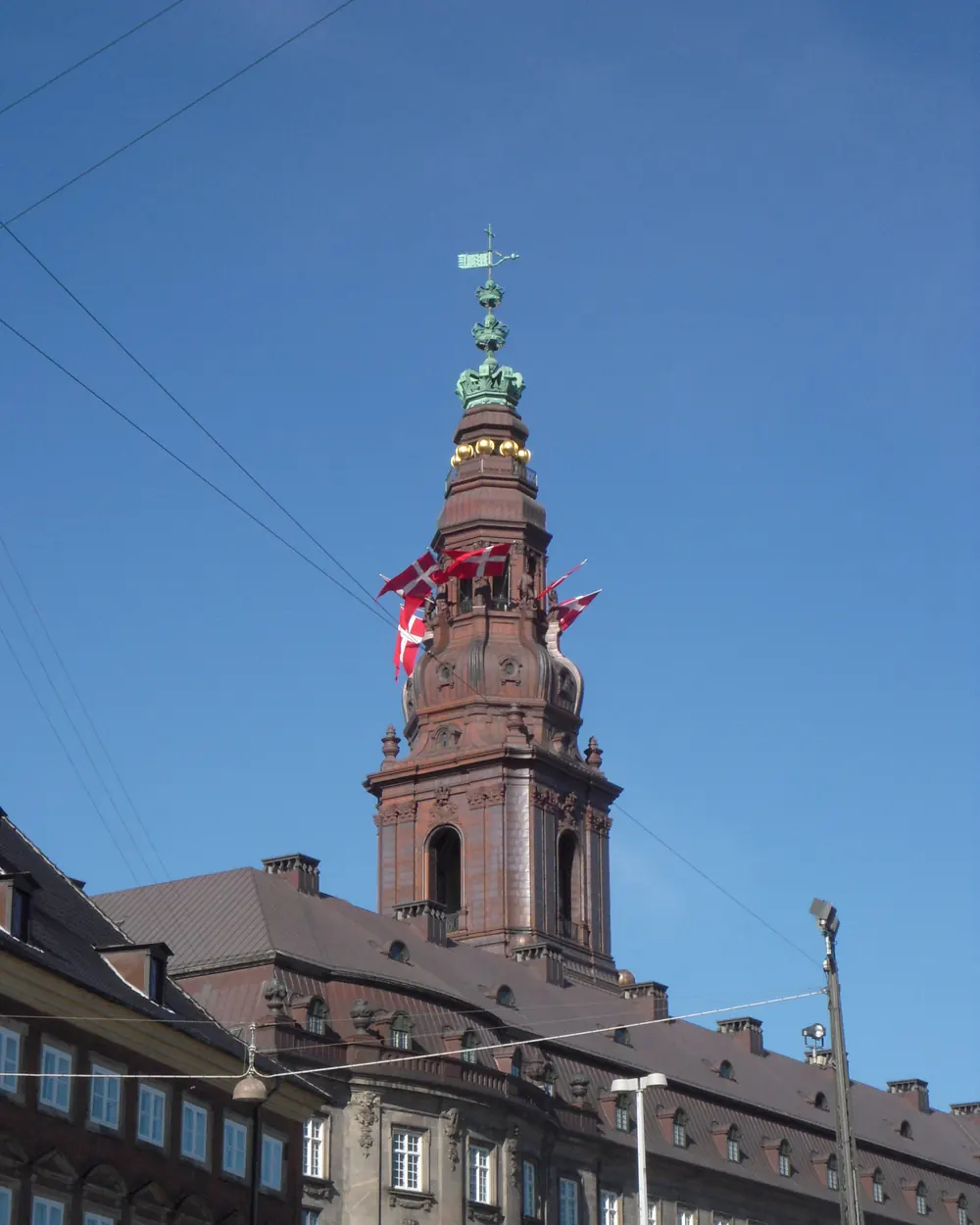 Christiansborgs tårn med dannebrogsflag mod blå himmel