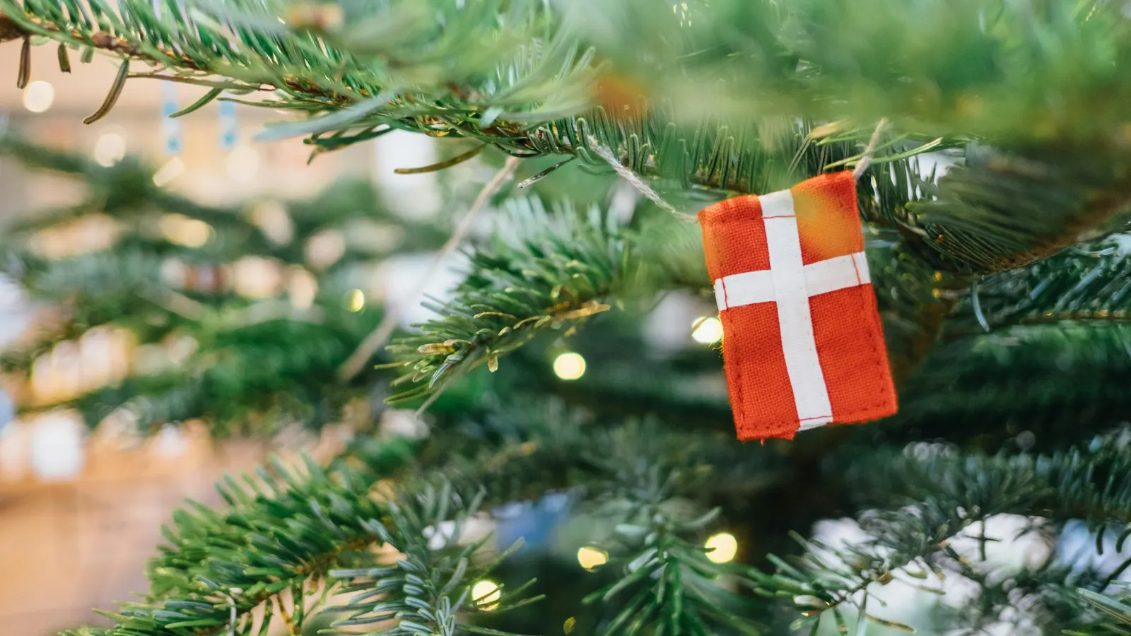 Lille dannebrogsflag hængt som pynt på en gren i et juletræ