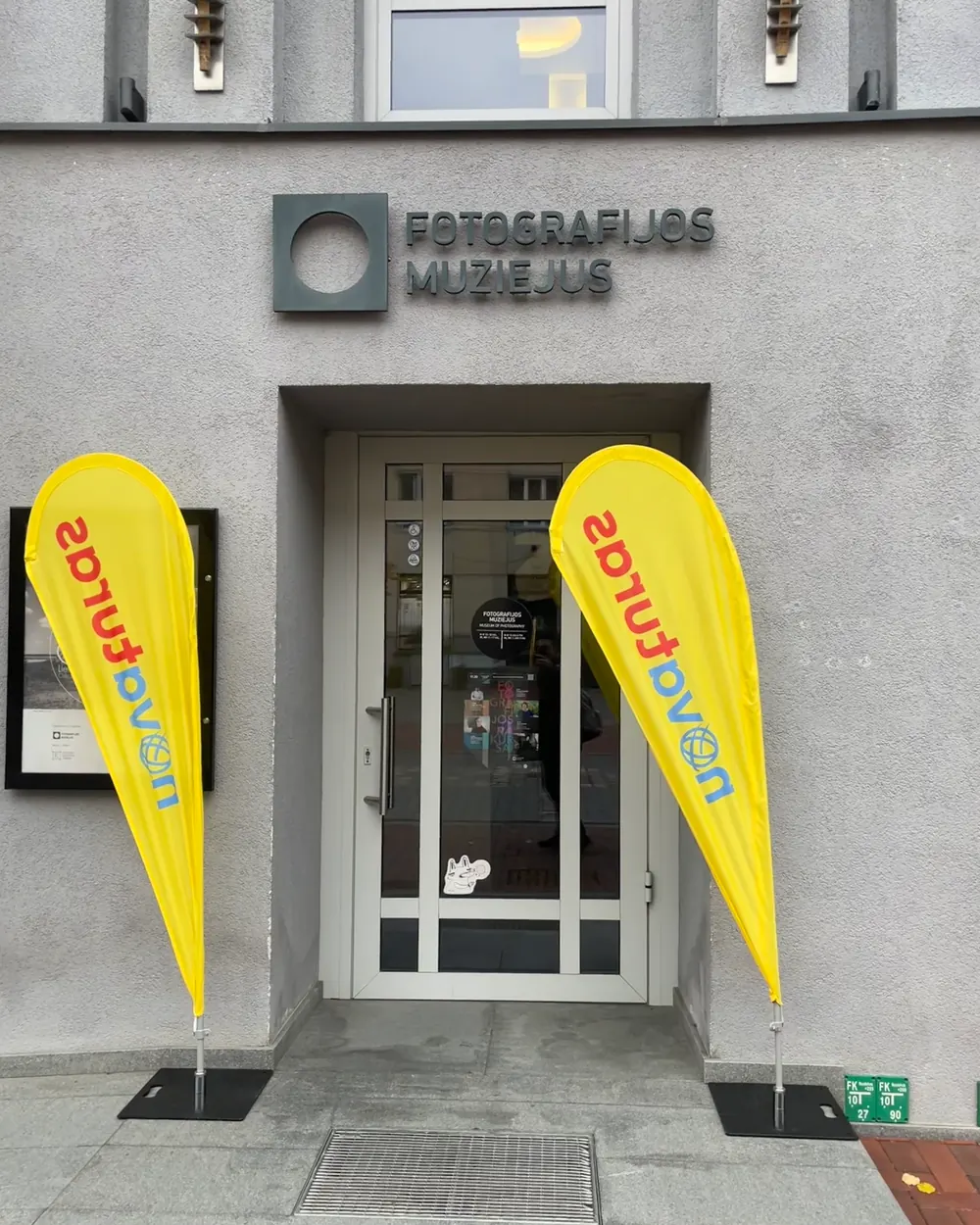 To gule beachflag med reklame på hver side af en indgangsdør