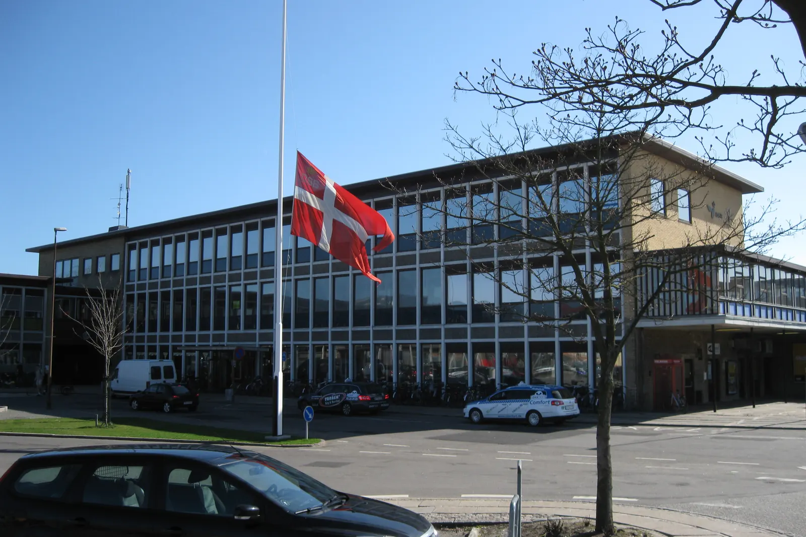Dannebrog på halv stang foran en stationsbygning
