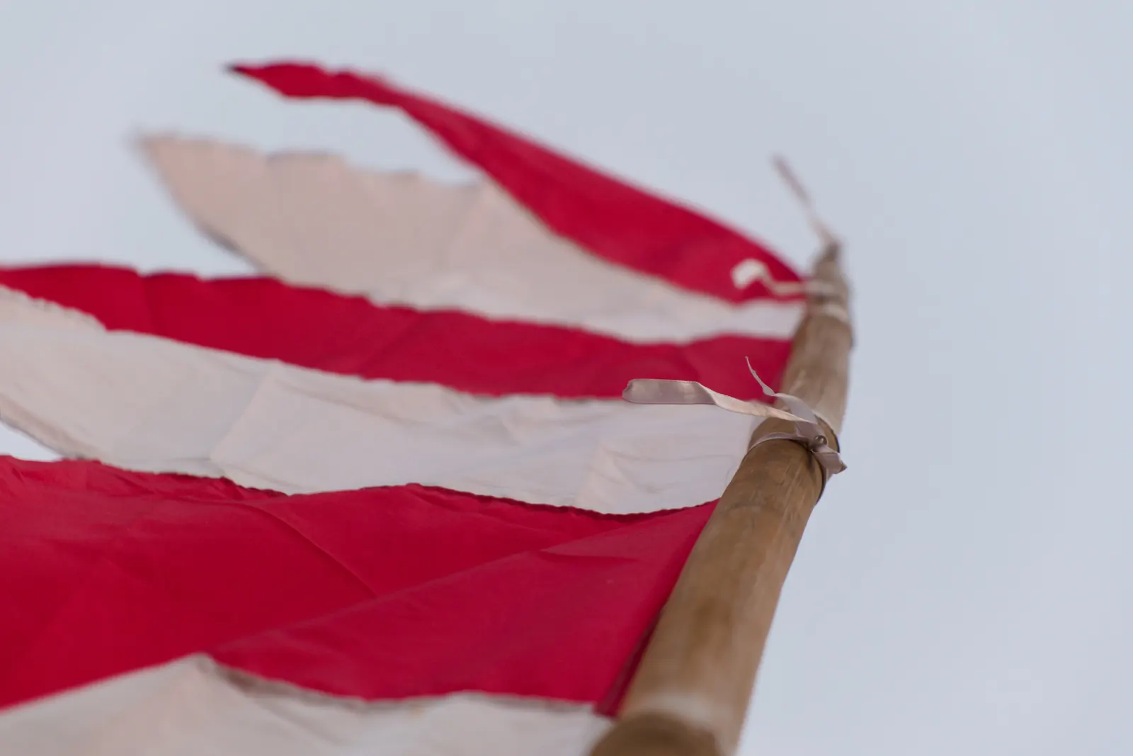 Flosset rødt og hvidt flag på en træstang