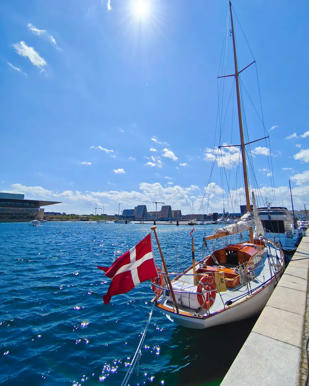 Dannebrog i agterstavnen på en sejlbåd ved en kaj