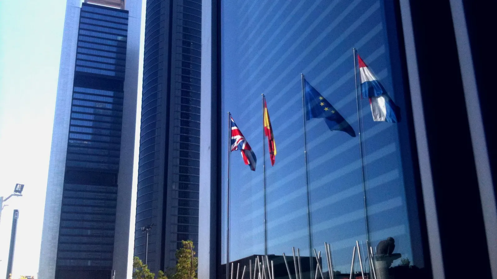 Banderas de varios países ante la fachada de cristal de la Torre Espacio, en Madrid