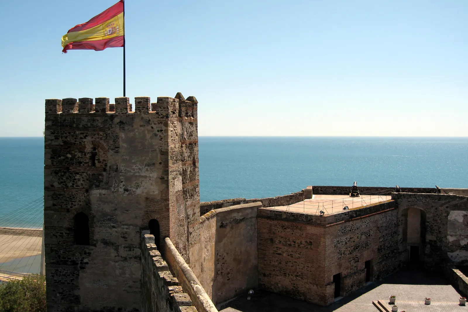 La bandera de España en lo alto de una torre del castillo de Sohail, en Fuengirola, junto al mar