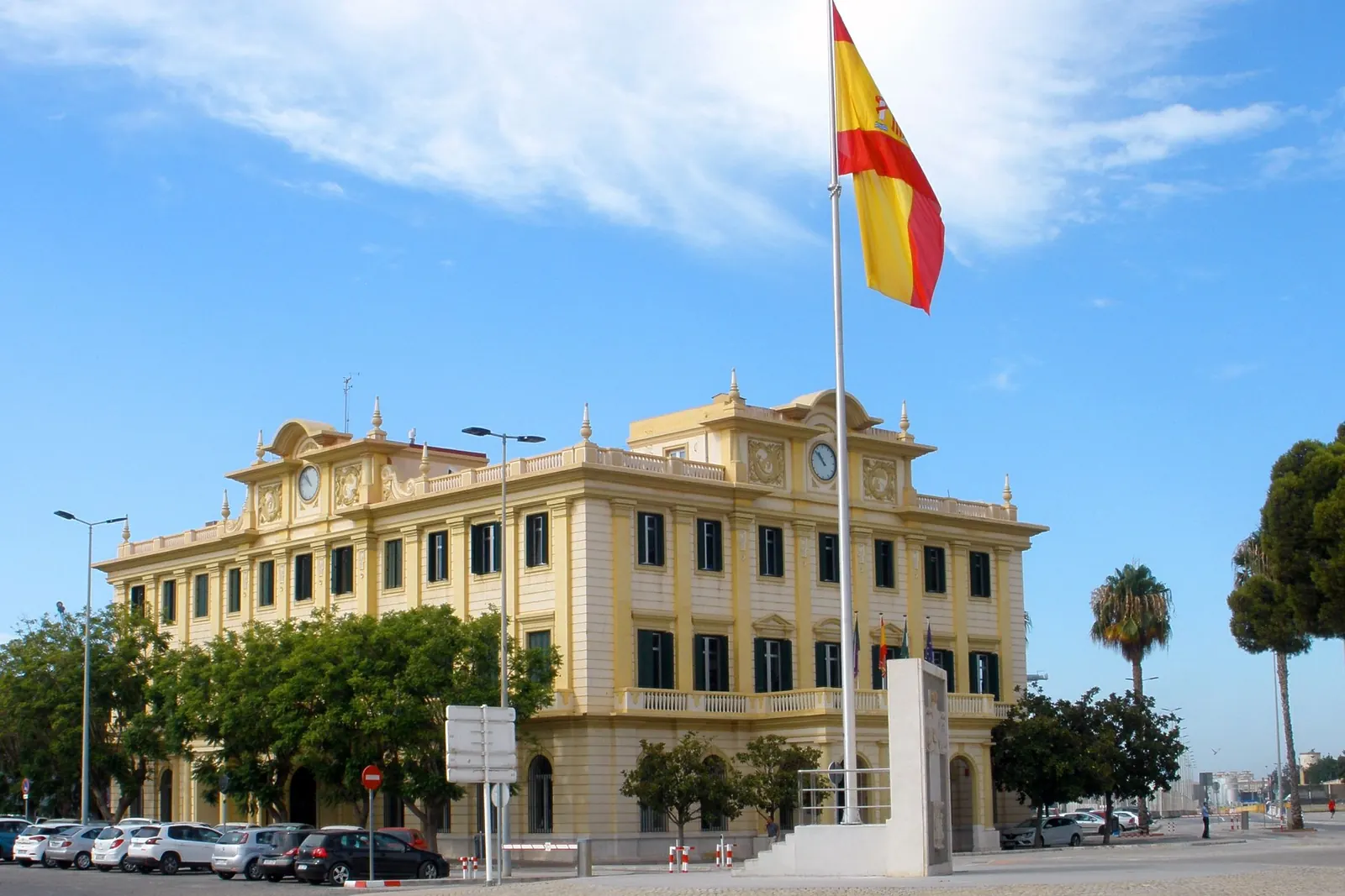 Edificio de la Autoridad Portuaria de Málaga con un alto mástil y la bandera de España