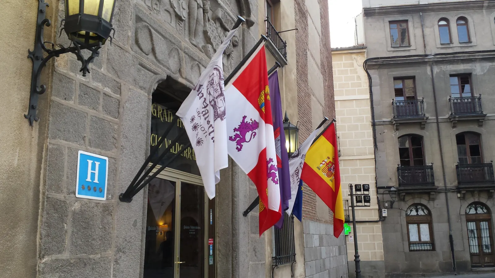 Fachada de un hotel en Ávila con banderas en astas sobre la entrada