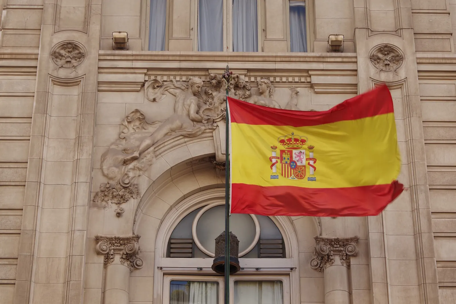 Una bandera de España en un asta de fachada sobre la ventana del Casino de Madrid