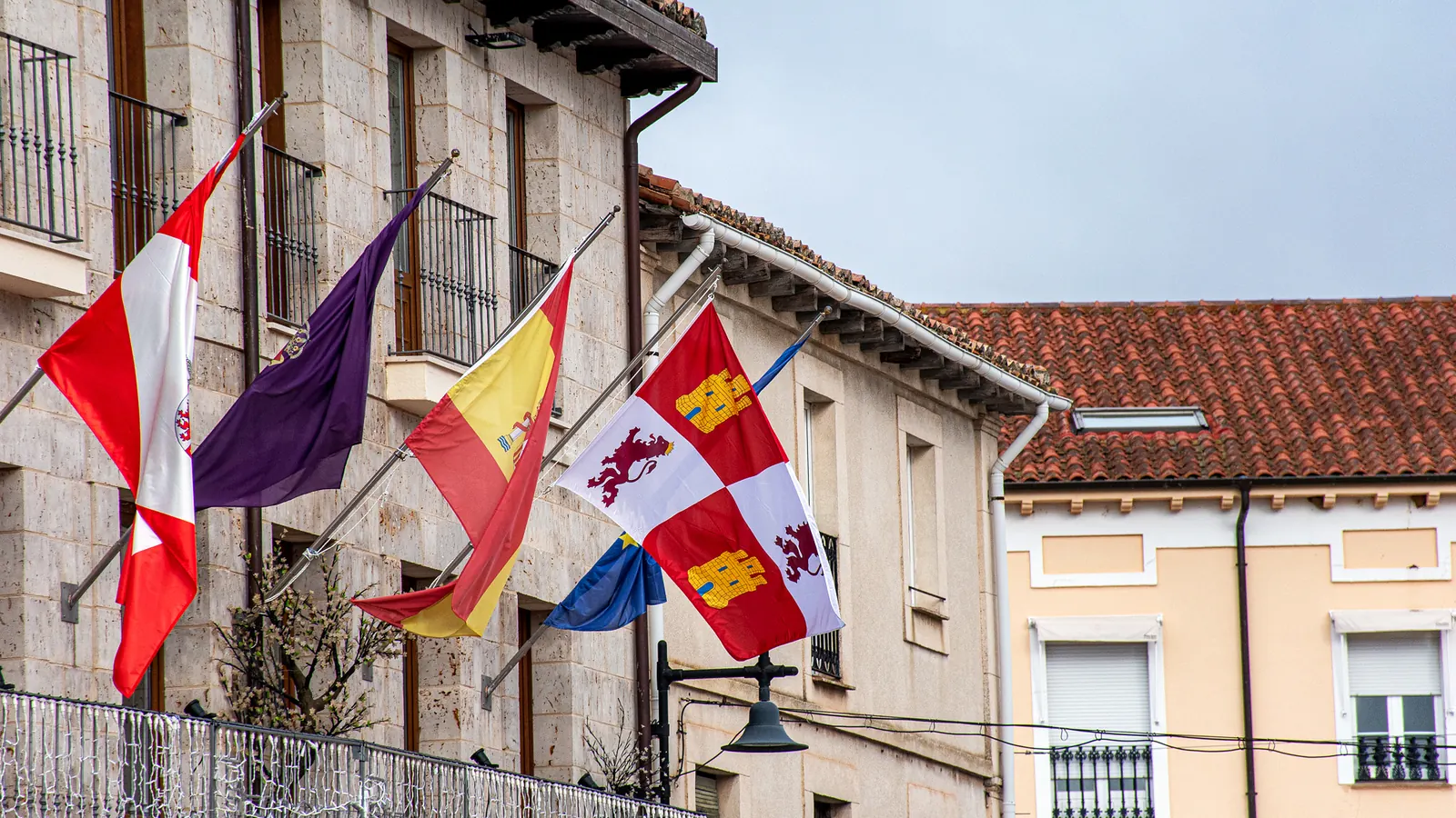 Balcón del Ayuntamiento de Villadiego con la bandera de España, la de Castilla y León y otras banderas